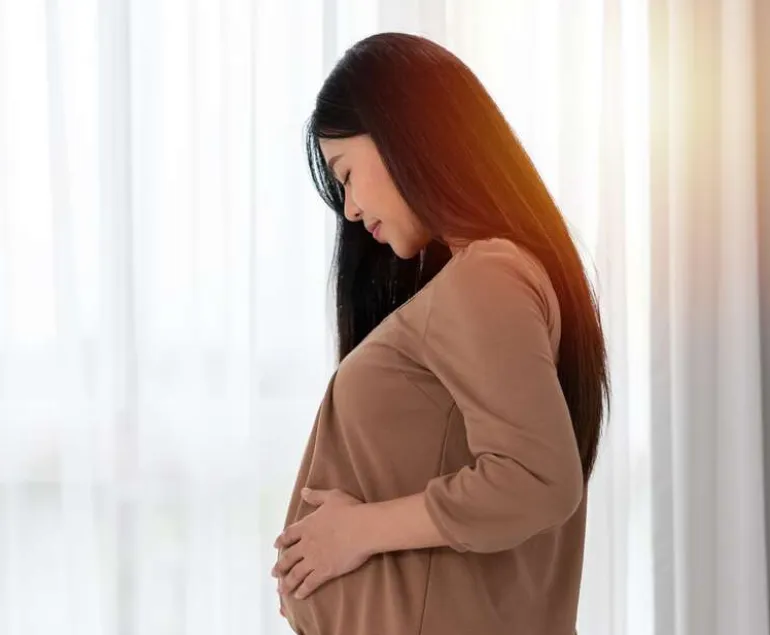 Indian-woman-during-pregnancy-gently-holding-her-baby-bump,-symbolising-successful-fertility-outcomes-and-PCOS-management