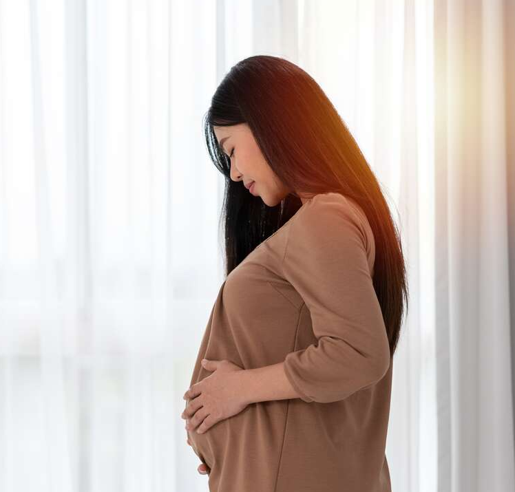 Indian-woman-during-pregnancy-gently-holding-her-baby-bump,-symbolising-successful-fertility-outcomes-and-PCOS-management
